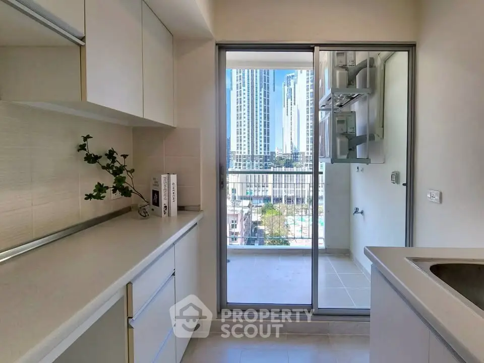 Modern kitchen with sleek cabinetry and balcony view in urban high-rise apartment.