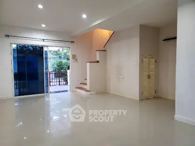 Spacious open-plan living area with modern staircase and large windows.