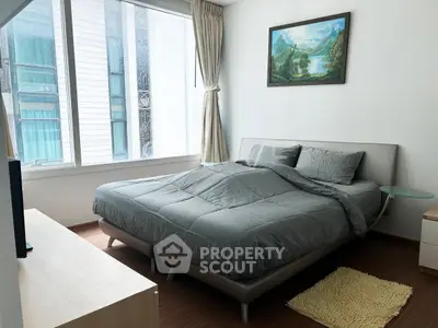 Cozy bedroom with modern decor and large window offering natural light