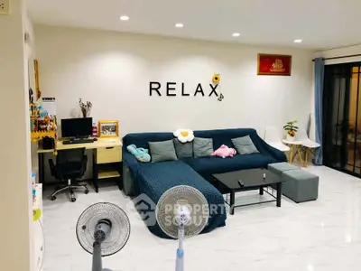 Modern living room with cozy sofa, stylish decor, and home office setup, perfect for relaxation and productivity.