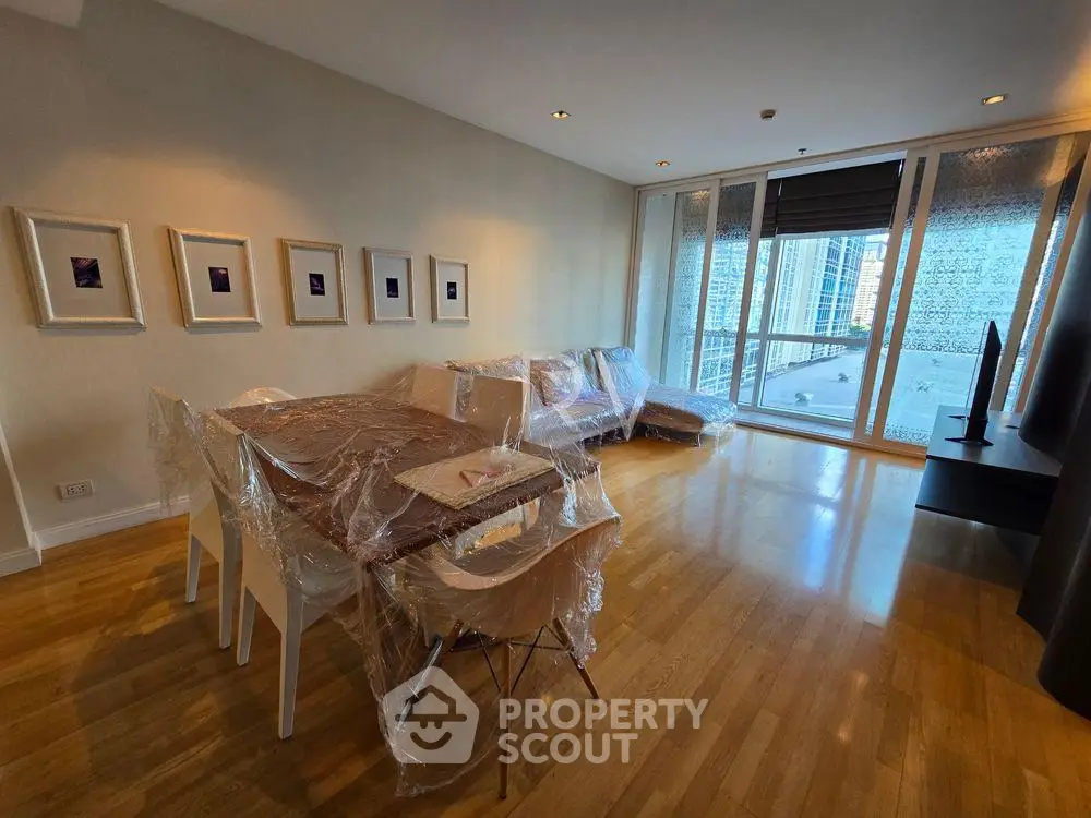 Spacious living room with modern furniture and large windows offering city views.