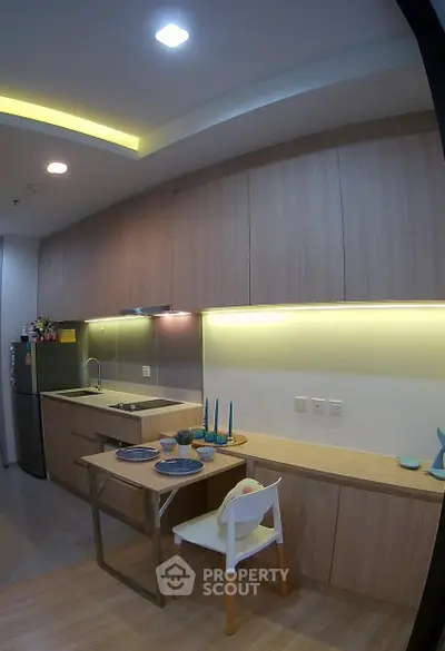 Modern kitchen with sleek cabinetry and integrated lighting, featuring a compact dining area.