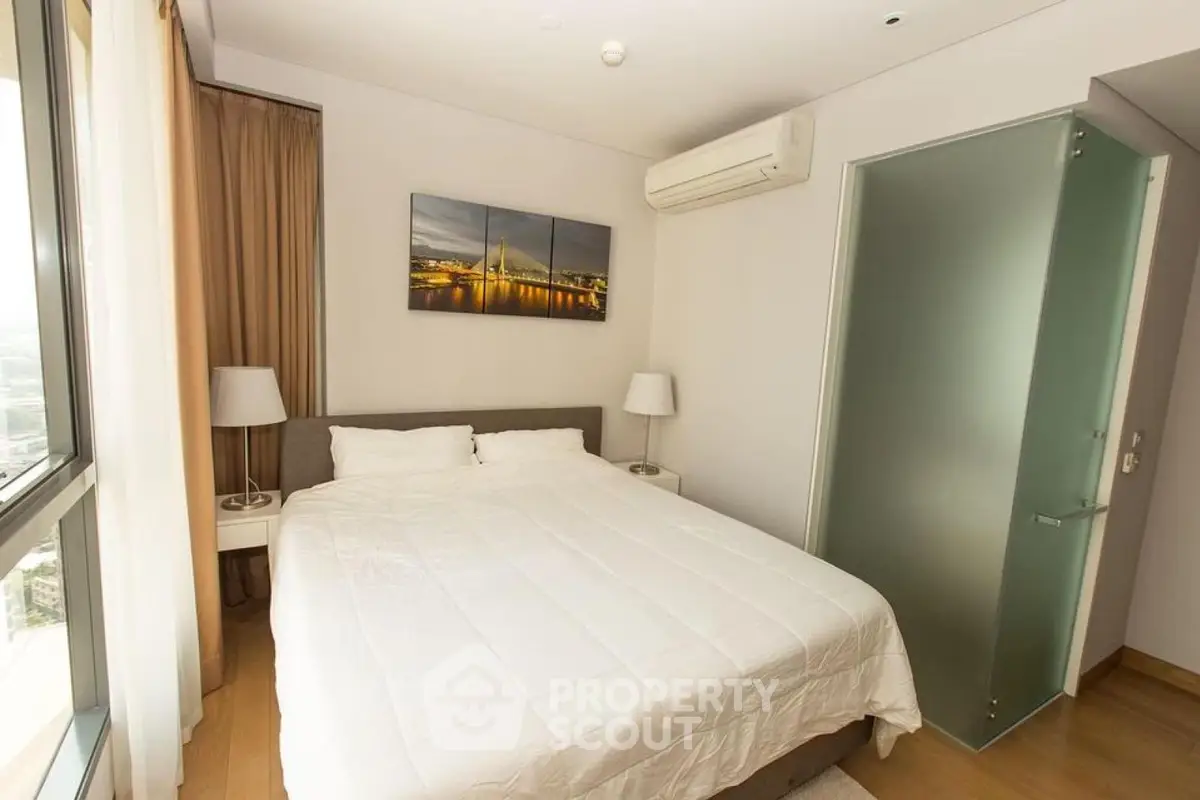 Modern bedroom with large window and stylish decor in a high-rise apartment.