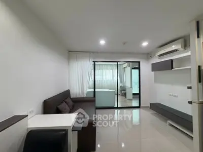 Modern living room with sleek design and open layout, featuring a view into a connected bedroom.