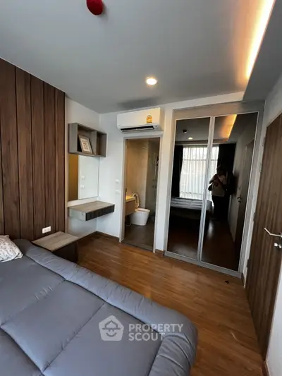 Modern bedroom with wooden accents, mirrored closet, and ensuite bathroom in stylish apartment.