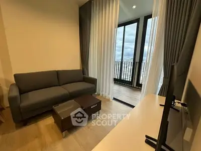 Modern living room with large windows and balcony view, featuring a cozy sofa and sleek TV setup.