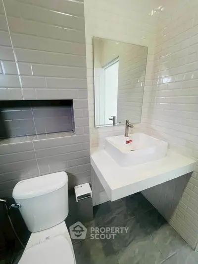 Modern bathroom with sleek white fixtures and stylish gray tile accents.