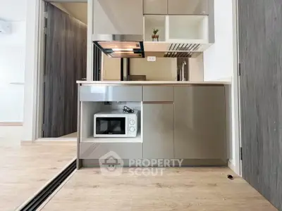 Modern compact kitchen with sleek cabinetry and built-in microwave in a stylish apartment.
