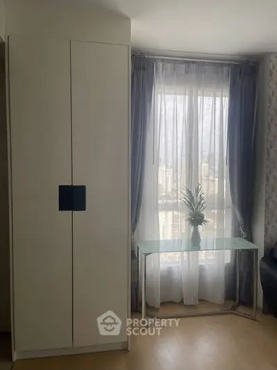 Bright living room with modern wardrobe and glass table near window with city view.