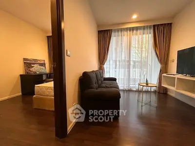 Cozy living room with dark sofa, TV, and large window with curtains in modern apartment.