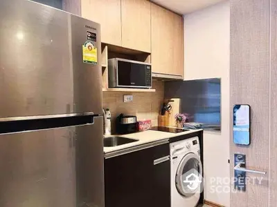 Modern compact kitchen with stainless steel fridge and washing machine