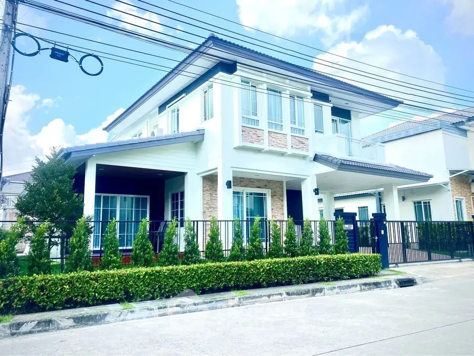 Stunning modern two-story house with lush greenery and spacious driveway.