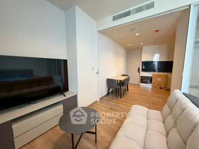Modern living room with sleek furniture and open layout, featuring a large TV and stylish decor.