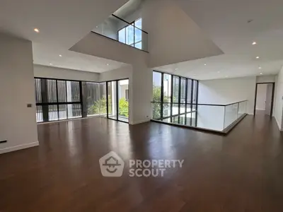 Spacious modern living room with high ceilings and large windows offering natural light.