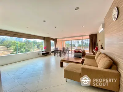 Spacious living room with large windows offering ample natural light and a panoramic view, complemented by a cozy sofa set and elegant dining area.