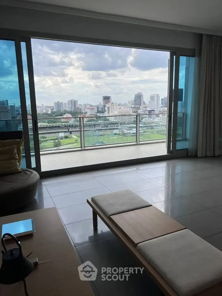 Spacious living room with stunning city view from large glass doors leading to balcony.