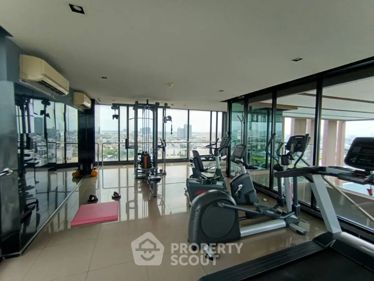 Spacious gym with modern equipment and panoramic city views in luxury high-rise.