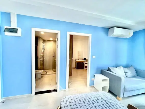 Modern living room with blue walls, air conditioning, and adjacent bathroom.