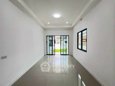 Spacious modern living room with large windows and glossy tiled floor, perfect for natural light.