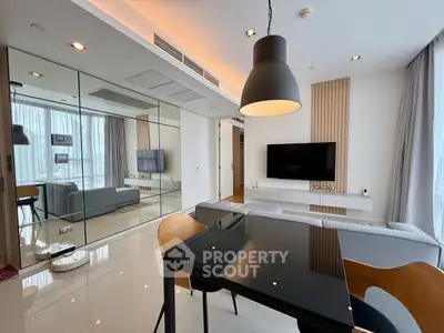 Modern living room with sleek design, mirrored wall, and large TV, perfect for urban living.