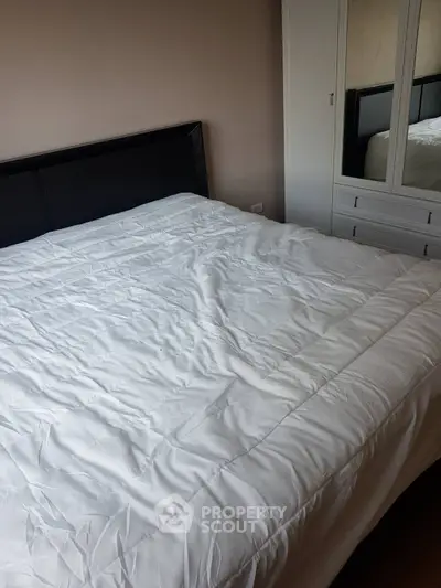 Cozy bedroom with white bedding and mirrored wardrobe, perfect for relaxation.