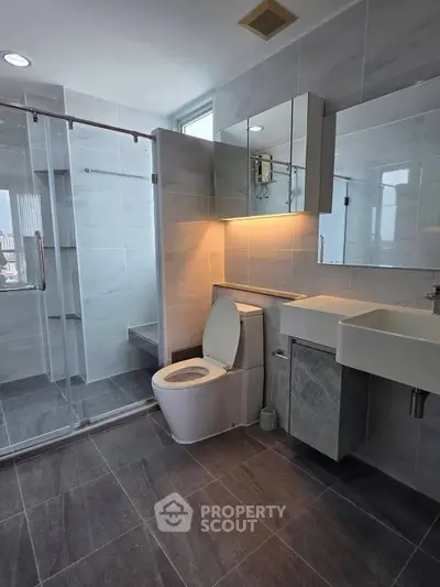Modern bathroom with glass shower and sleek fixtures in a contemporary apartment.