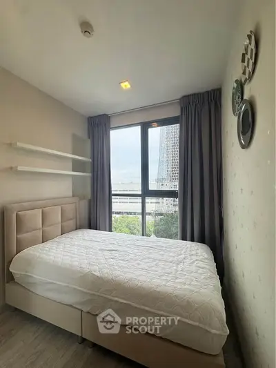 Cozy bedroom with large window offering city view, modern decor, and ample natural light.