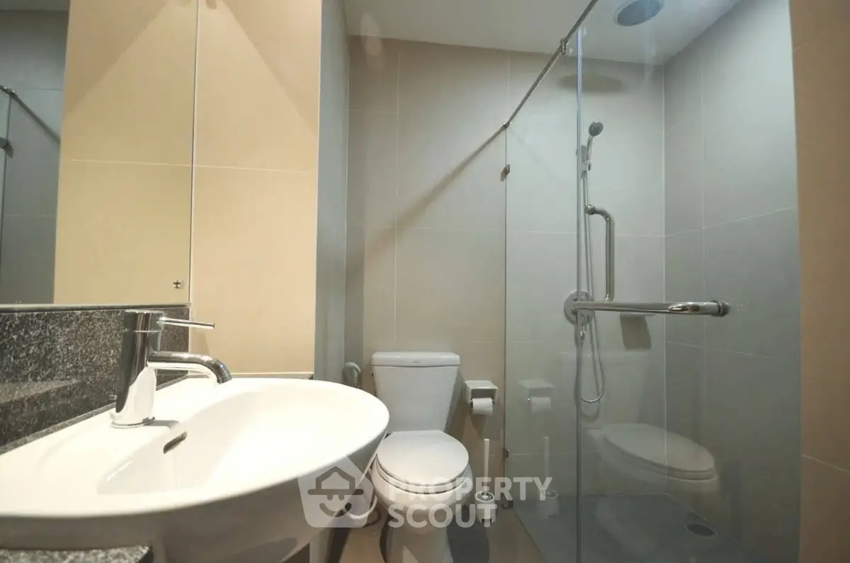 Modern bathroom with glass shower and sleek fixtures in contemporary apartment.