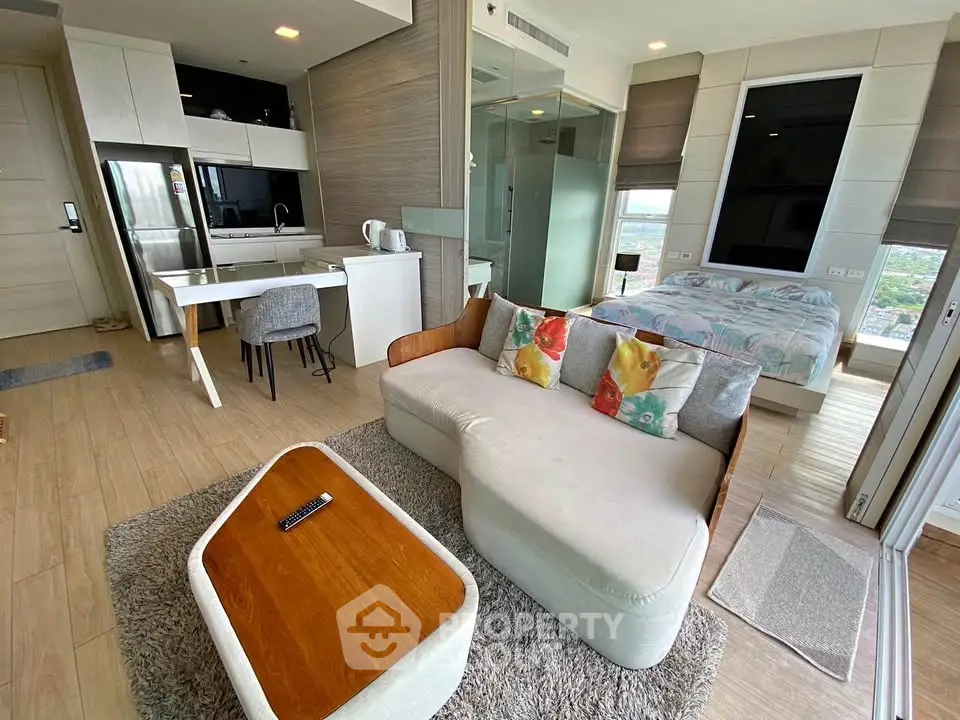 Modern open-plan studio with cozy living area, stylish kitchen, and comfortable bedroom, featuring large windows and natural light.