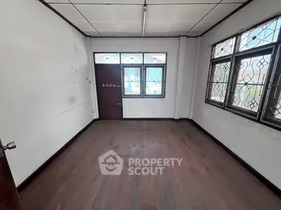 Spacious empty room with wooden flooring and large windows, ideal for customization.