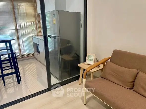 Modern living room with glass partition and sleek kitchen area.