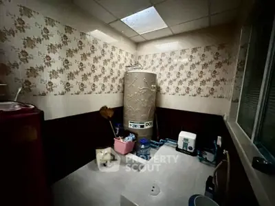 Utility room with water heater and storage space in a residential property.
