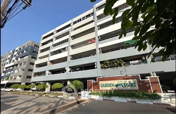 Modern multi-story residential building with lush landscaping and clear signage.