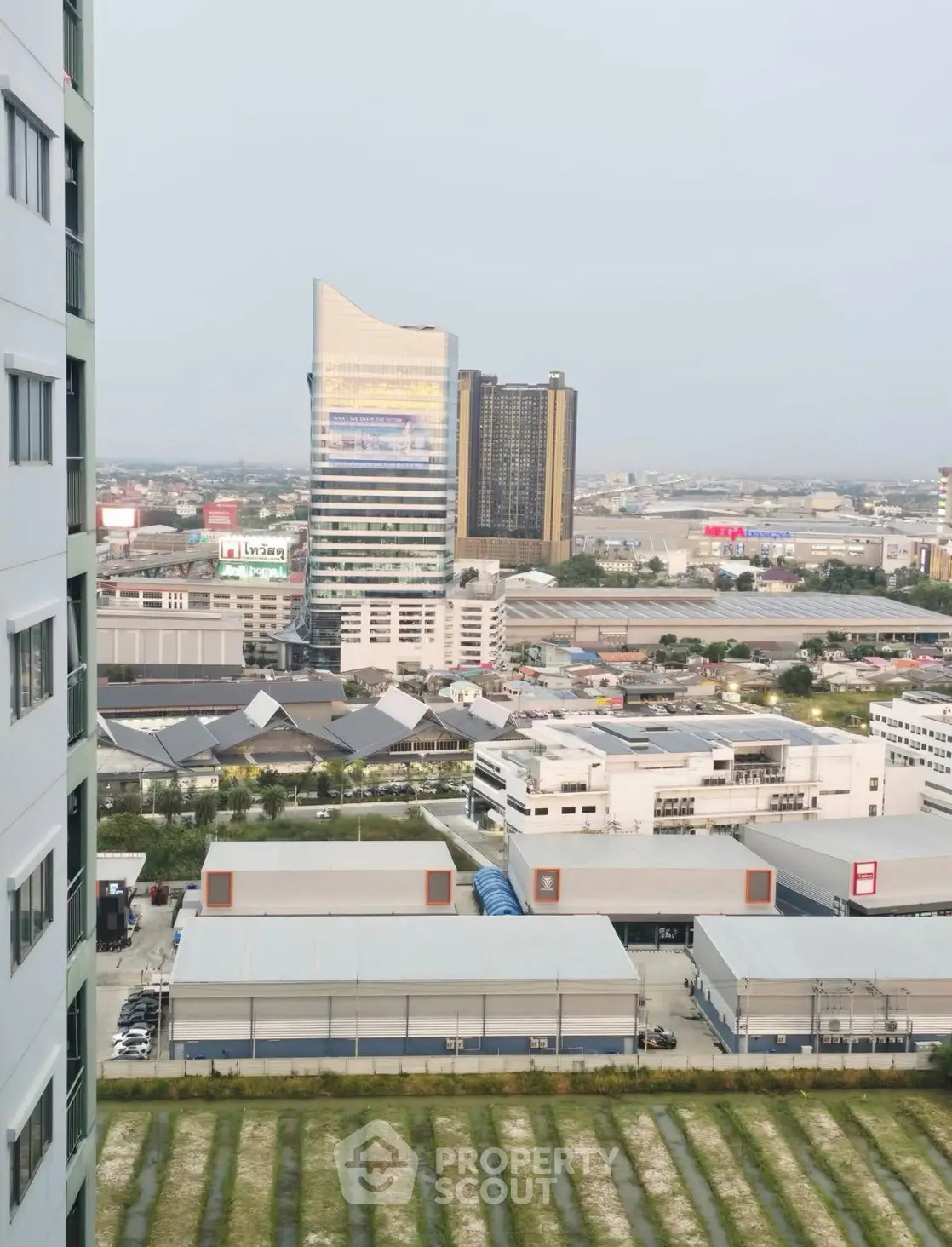 Stunning cityscape view from high-rise building with modern architecture and lush green surroundings.