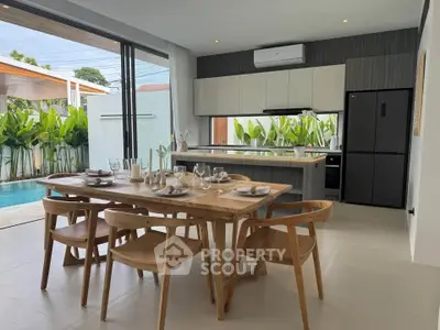 Modern open-plan kitchen and dining area with pool view, featuring sleek cabinetry and elegant dining set.