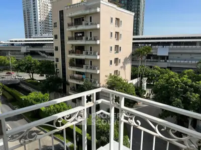 Spacious balcony with city view overlooking modern buildings and lush greenery.
