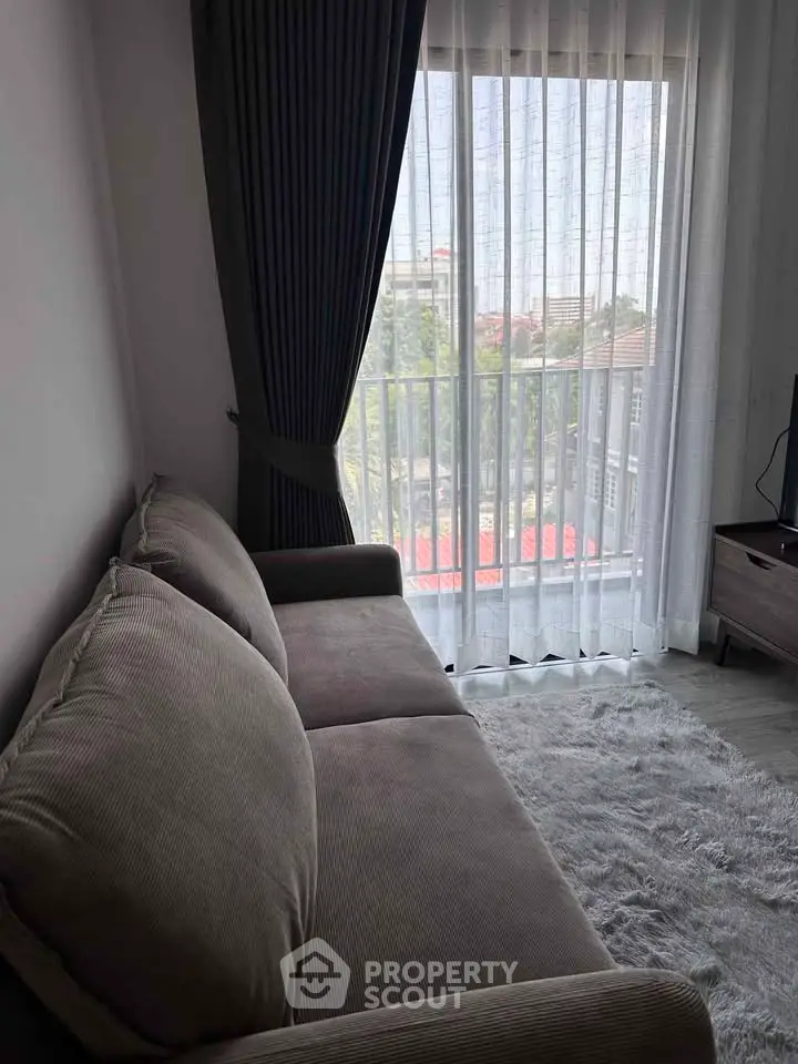 Cozy living room with plush sofa and large window offering city view.