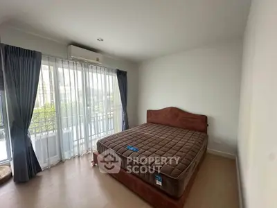 Spacious bedroom with large window and balcony access in modern apartment.