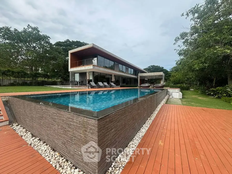 Luxurious modern villa with stunning infinity pool and spacious deck surrounded by lush greenery.