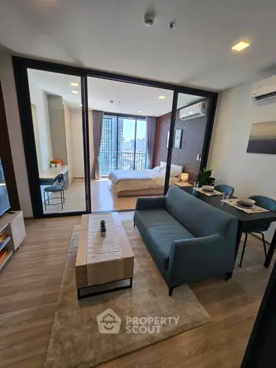 Modern open-plan living room with stylish furniture and a view into a cozy bedroom, perfect for urban living.