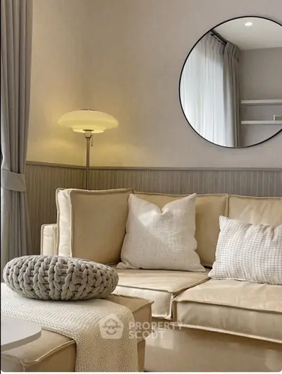Elegant living room with beige sofa, round mirror, and stylish lamp for a cozy ambiance.