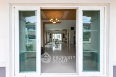 Spacious modern living room with large glass doors and elegant lighting.