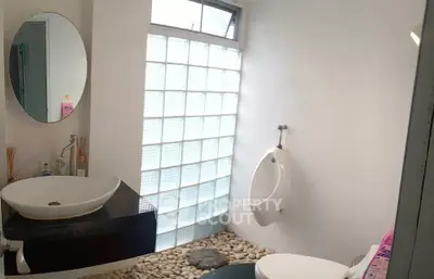 Modern bathroom with unique pebble flooring and glass block wall for natural light.