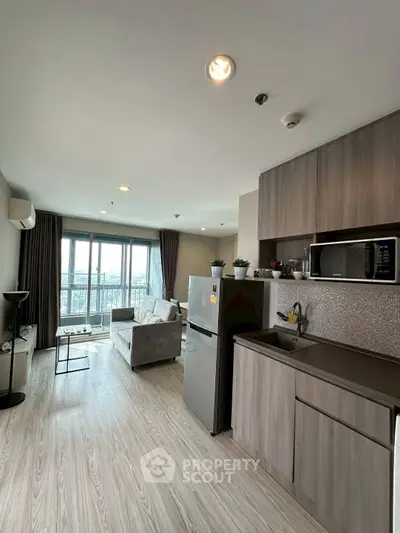Modern open-layout kitchen and living room with city view, featuring sleek cabinetry and cozy seating area.
