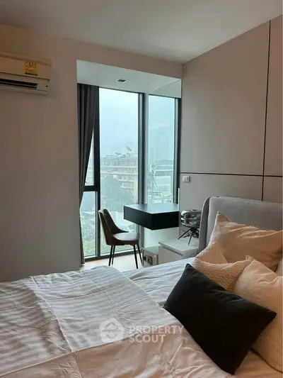 Modern bedroom with large window and city view, featuring cozy bed and stylish decor.