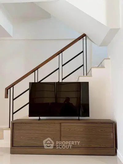 Modern interior with sleek staircase and stylish TV console in a contemporary home setting.