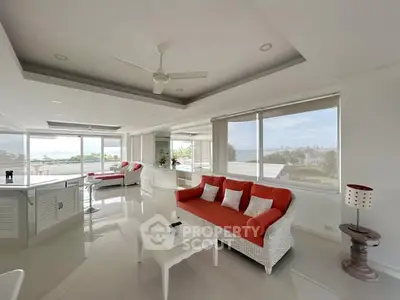 Spacious living room with modern white and red decor and panoramic windows