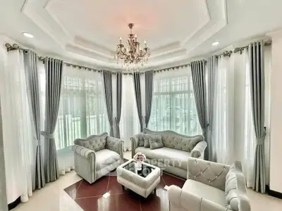Elegant living room with luxurious furniture and chandelier, featuring large windows and stylish curtains.