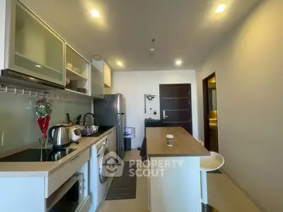 Modern kitchen with island, washing machine, and sleek appliances in a cozy apartment.