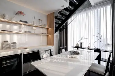 Modern kitchen with sleek design, open layout, and elegant dining area under staircase.